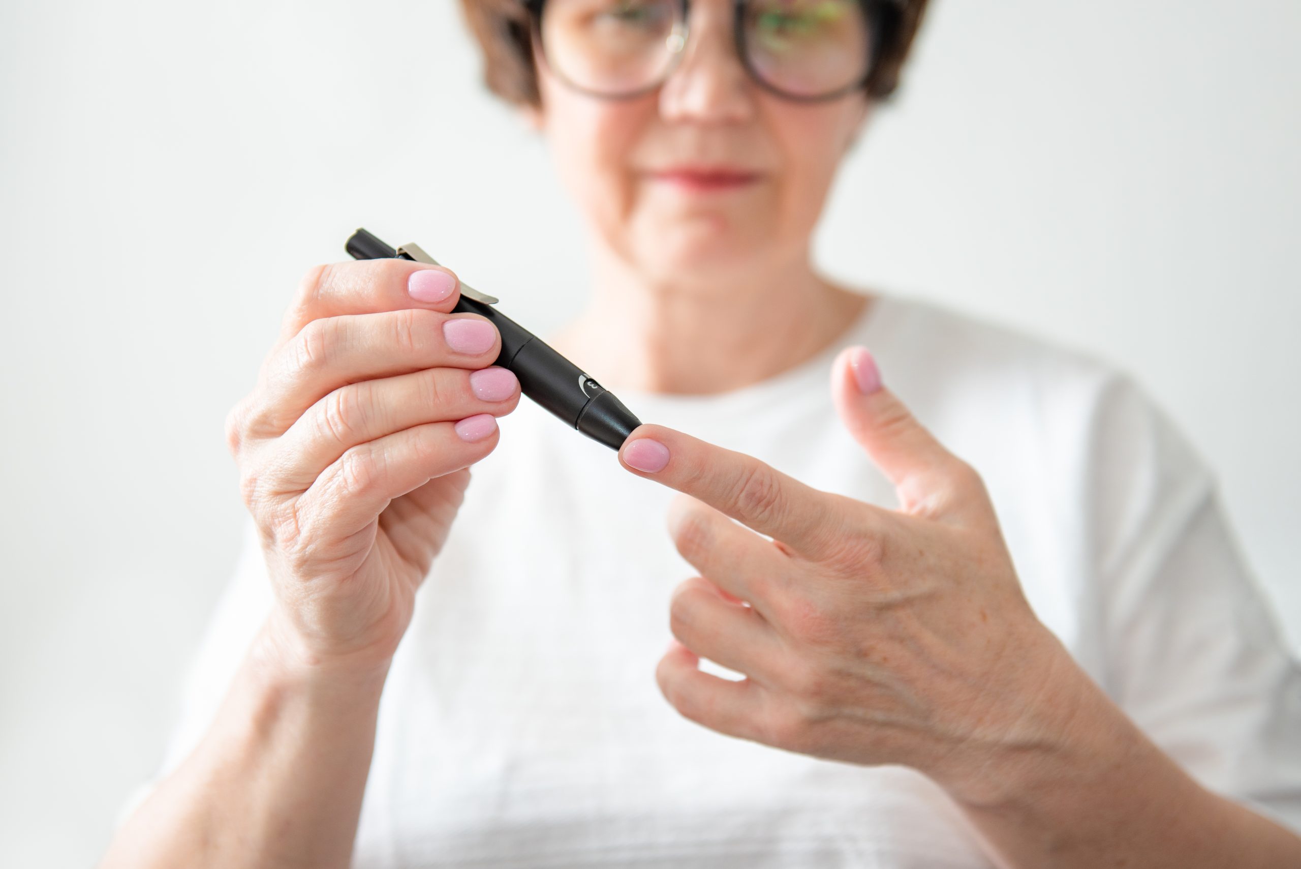 Starija žena vadi krv iz prsta kako bi proverila nivo šećera